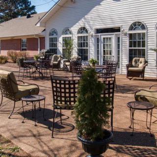 A sunny patio with outdoor seating and a view of a building.