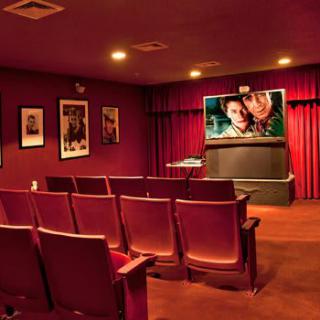 A cozy home theater with red seating and movie posters on the walls.