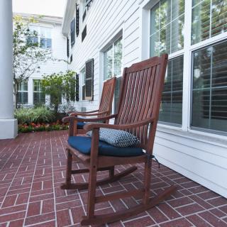 Wooden rocking chairs on a brick porch of a house.