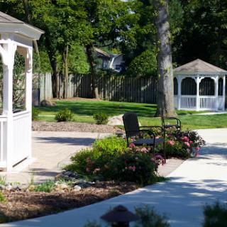 A serene garden scene featuring two gazebos, colorful flower beds, and a welcoming pathway.