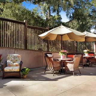 A sunny outdoor patio with comfortable chairs and tables under large umbrellas.