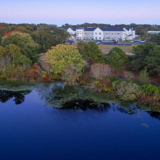A serene view of a building surrounded by autumn trees and a calm lake reflecting the scenery.