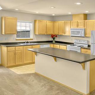 A modern kitchen with light wood cabinets and a large island.