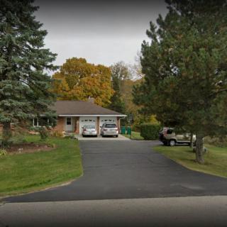 A suburban house with a driveway, surrounded by trees in autumn.