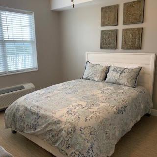 A neatly arranged bedroom with a bed under decorative wall art.