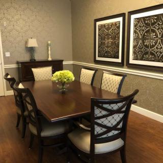 A neatly arranged dining room featuring a wooden table, cushioned chairs, and decorative artwork on the walls.
