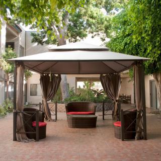 A cozy outdoor seating area under a gazebo surrounded by greenery.
