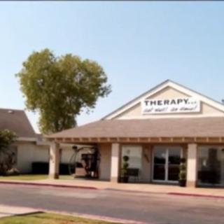 A therapy center building with a sign, located outdoors on a clear day.
