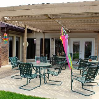 A backyard patio with tables and chairs under a pergola.