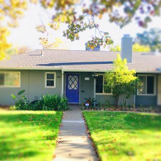 A charming suburban house with a blue front door and a well-maintained front yard on a sunny day.