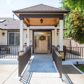 A residential entrance featuring a ramp and columns leading to the front door.