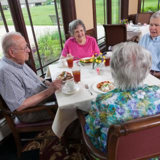 A group of senior citizens enjoying a meal and conversation at a restaurant.