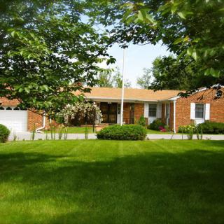 A charming brick house surrounded by a lush green lawn and trees.
