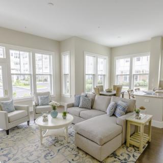 A bright and modern living room with large windows and light-colored furniture.