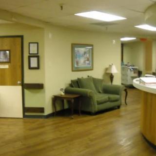 A hospital waiting area with a green sofa and reception desk.