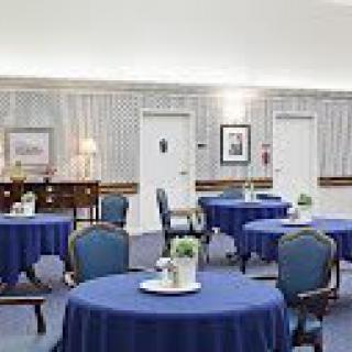 An elegantly decorated dining area featuring round tables with blue tablecloths and classic chairs.