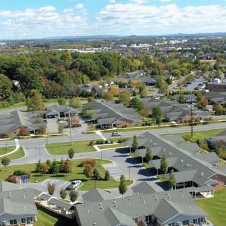 Aerial view of a suburban neighborhood with residential houses and green spaces under a partly cloudy sky.