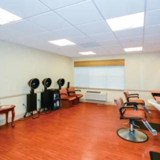 An empty hair salon with chairs, hair dryers, and wooden flooring.