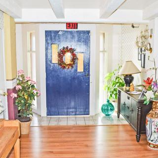A cozy interior featuring a blue door adorned with a wreath, surrounded by plants and furniture.