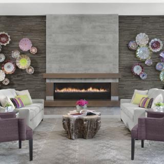 A modern living room with a central fireplace, featuring decorative wall plates and stylish seating arrangements.