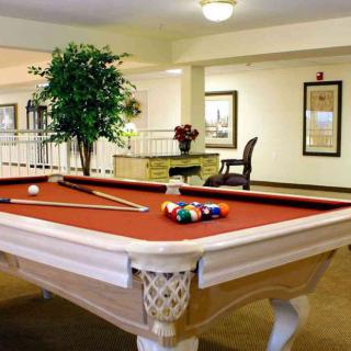 A cozy indoor recreation room featuring a red-felt pool table equipped with cue sticks and a set of billiard balls.