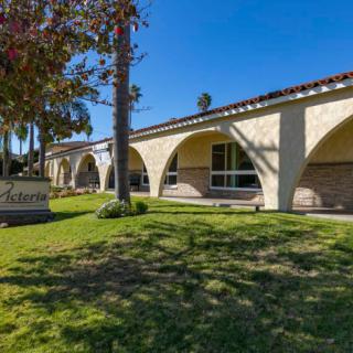 A sunny day highlights the arched design of a building surrounded by grass and trees.