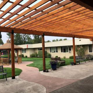 A well-maintained courtyard featuring a wooden pergola, pathways, and outdoor seating.
