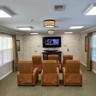 A cozy home theater room with leather seating and a large TV screen.