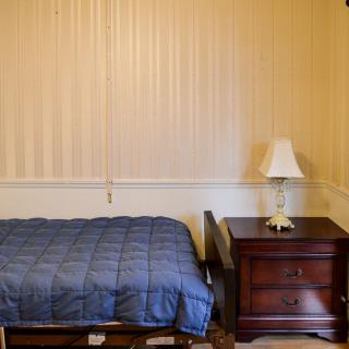 A simple bedroom with a bed, nightstand, and lamp.