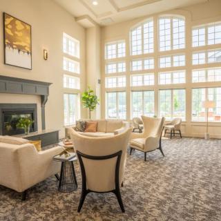 A spacious, sunlit living room with comfortable seating and large windows.