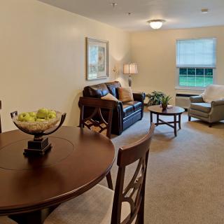 A cozy living room with a sofa, coffee table, and dining area.