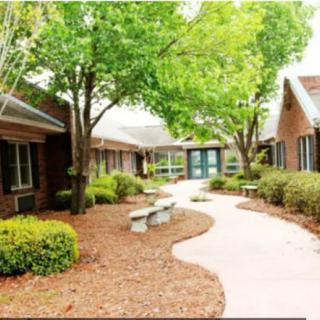A serene courtyard featuring a winding pathway, surrounded by lush trees and neatly maintained landscaping.