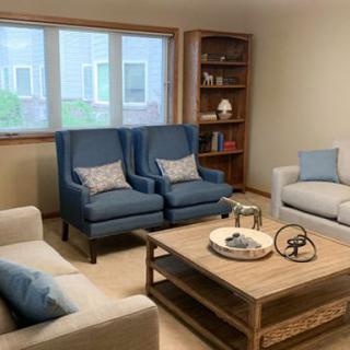 A cozy and elegantly furnished living room with blue armchairs, a neutral sofa, and a wooden coffee table.