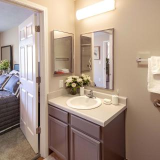 A well-lit bathroom with a vanity and sink, featuring decorative flowers and neatly placed towels.