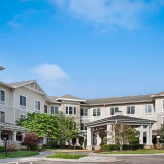 A large residential building with a neatly landscaped entrance under a clear blue sky.