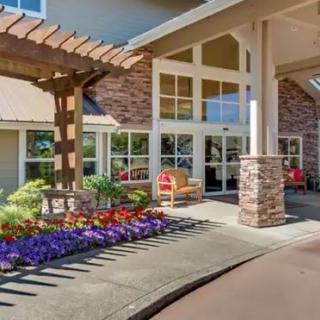 A beautifully landscaped building entrance with vibrant flowers and cozy outdoor seating.