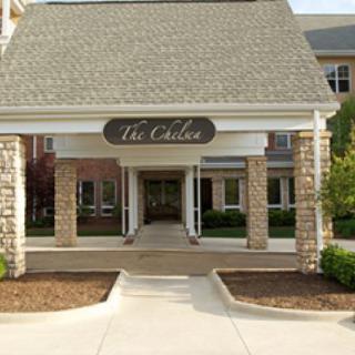Entrance to a building with stone pillars and a sign that reads 'The Chelsea'.