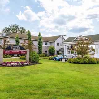 A picturesque view of a hotel exterior with a well-manicured lawn and clear skies.