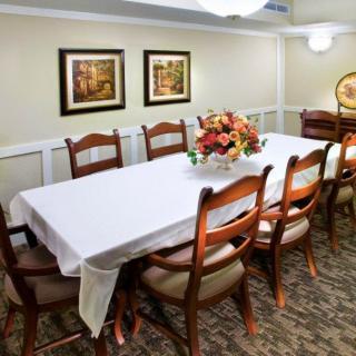 A neatly arranged dining room with a long table, chairs, and decorative elements.