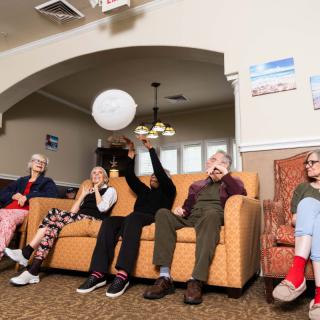 A group of seniors playing a ball game in a cozy living room setting.