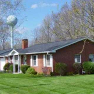 A brick house with a well-maintained lawn and a water tower in the background.
