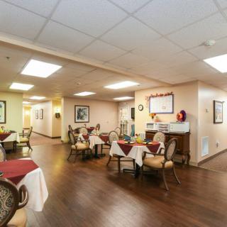 An indoor dining area with neatly arranged tables and chairs on a wooden floor.