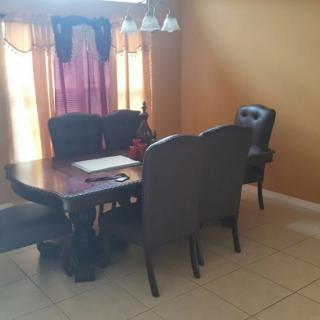 A cozy dining room setup with a wooden table, chairs, and warm lighting.