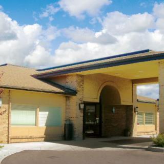A modern brick building with a covered entrance and a cloudy sky above.