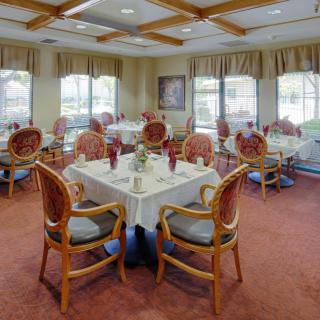A formal dining room with elegantly set tables and upholstered chairs.