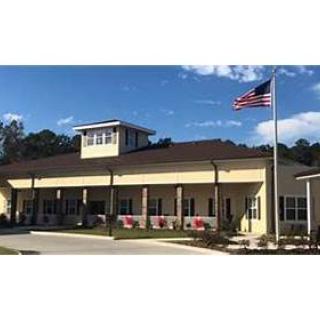 A well-designed community center with an American flag waving in front under a clear blue sky.