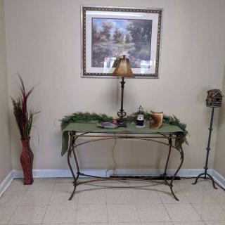 A decorated hallway corner with a table, lamp, and wall art.