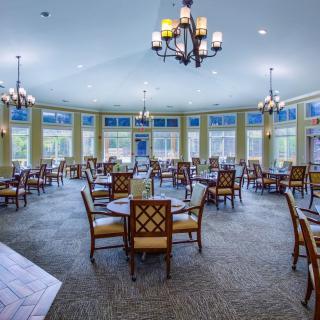A spacious dining room with elegant chandeliers and large windows.