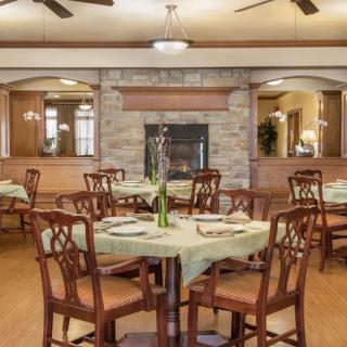 An elegant dining room with neatly set tables and a cozy fireplace.