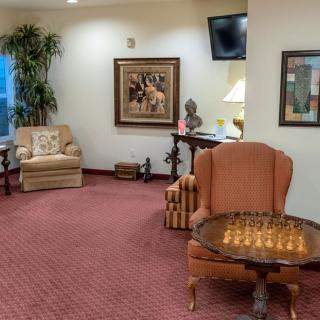 A cozy living room with plush seating, a chess board on a table, and decorative artwork.